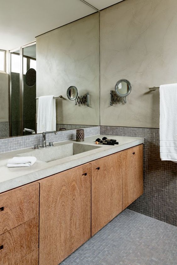 Banheiro com pastilha de vidro cinza no piso e meia parede. Meia parede de cima revestida com cimento queimado.