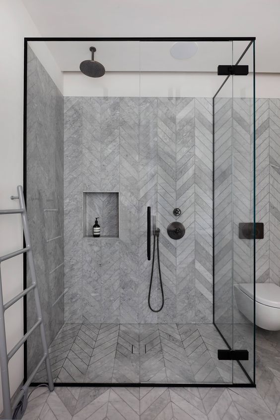 Banheiro com mármore cinza tipo espinha de peixe no piso e nas paredes