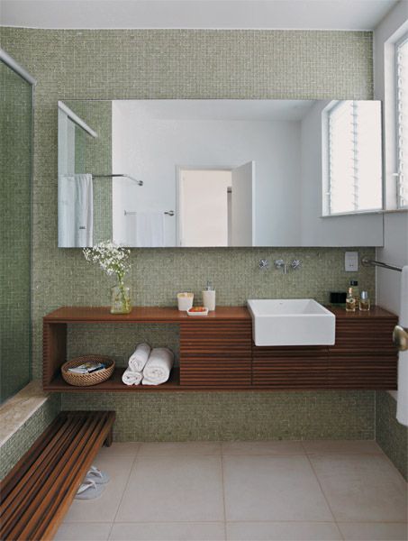 Banheiro com pastilhas de vidro verdes na parede da bancada e do box