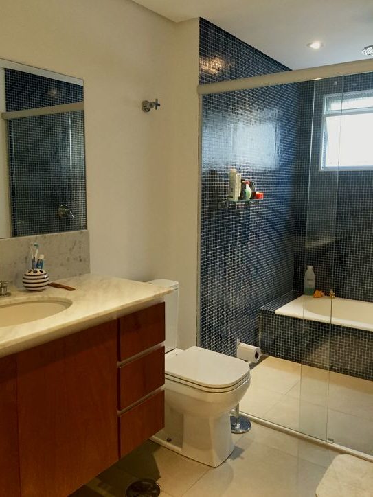 Banheiro com pastilha azul marinho no box e banheira