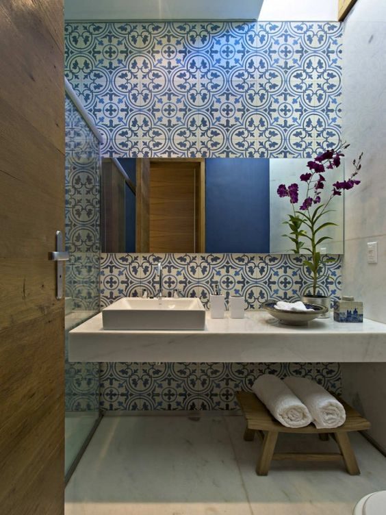 Banheiro com ladrilho hidráulico branco e azul na parede da bancada e do box