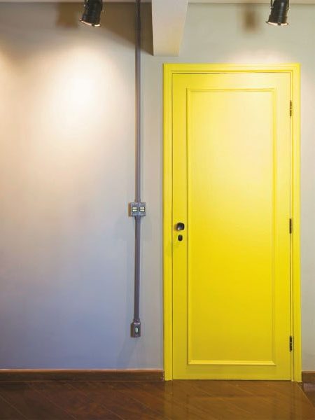 Cores: Porta de madeira pintada de amarelo com parede cinza
